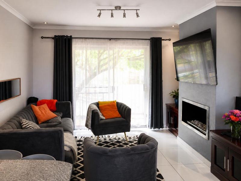 A well-maintained living room featuring a modern built-in fireplace, sleek tiled flooring, and large sliding glass doors providing natural light.