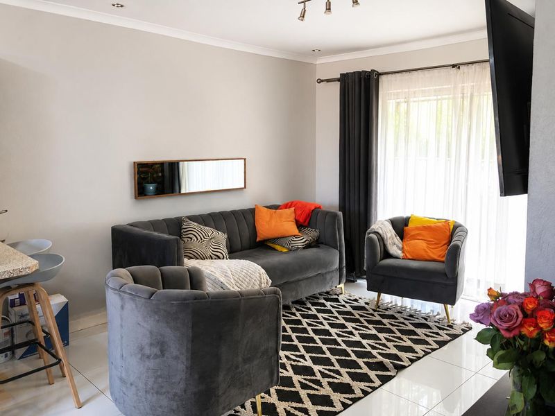 A bright and modern living room featuring tiled flooring, recessed ceiling lighting, and a large sliding glass door providing access to the exterior.