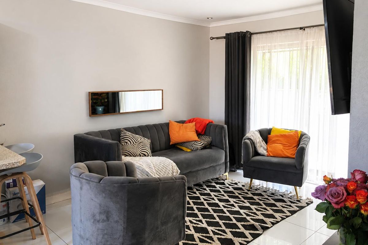 A bright and modern living room featuring tiled flooring, recessed ceiling lighting, and a large sliding glass door providing access to the exterior.