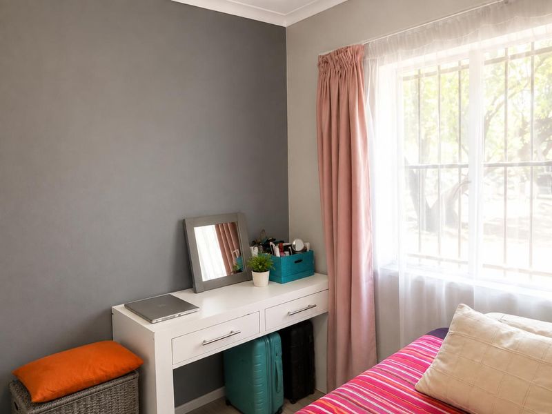 A bedroom featuring a grey accent wall, window with security bars, and coving detail.
