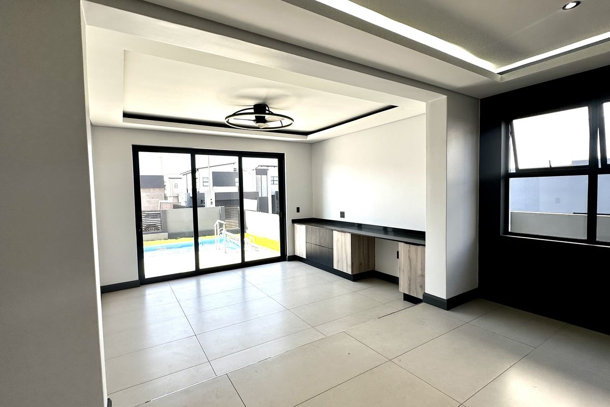 Spacious living area featuring modern recessed ceiling lighting, large sliding glass doors leading to the pool area, and sleek built-in cabinetry.