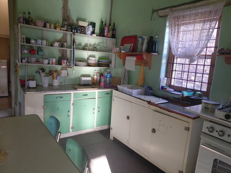 A dated kitchen featuring original cabinetry, a sink, and a freestanding stove, requiring significant renovation and cosmetic updates to improve functionality and aesthetic appeal.