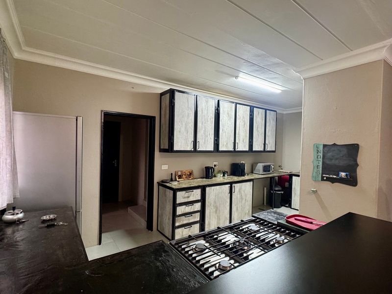 A functional kitchen featuring industrial-style cabinetry with wood-look finishes, dark countertops, and a built-in gas hob.
