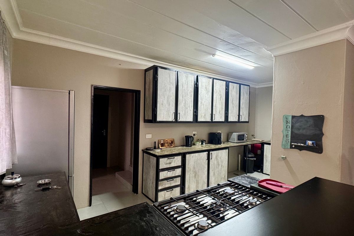 A functional kitchen featuring industrial-style cabinetry with wood-look finishes, dark countertops, and a built-in gas hob.