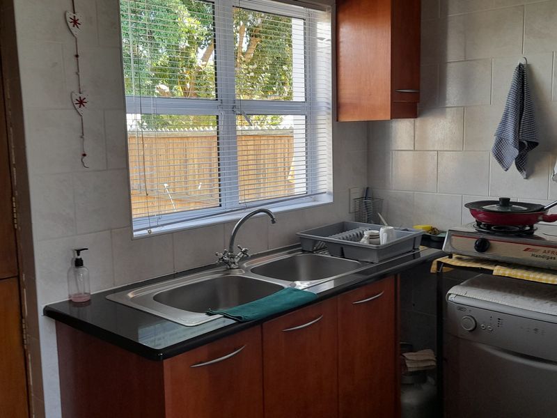 A functional kitchen area featuring a double bowl stainless steel sink, laminate cabinetry, and tiled splashback, providing a practical workspace.