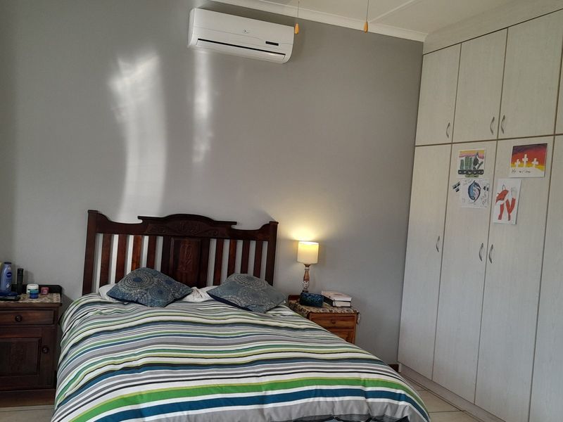 A functional bedroom featuring built-in cupboards and a wall-mounted split-system air conditioning unit.