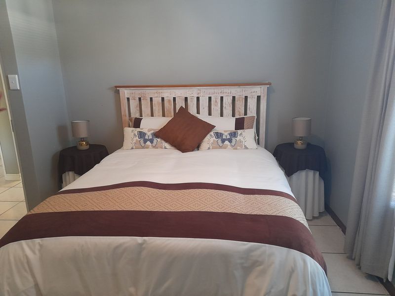 A neutrally painted bedroom featuring tiled flooring and a simple layout, offering a clean and functional space.