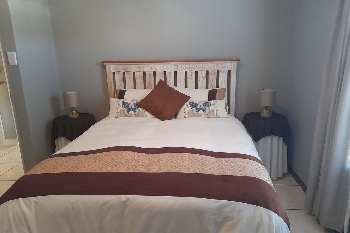 A neutrally painted bedroom featuring tiled flooring and a simple layout, offering a clean and functional space.