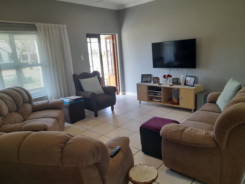 A living room featuring tiled flooring, neutral wall tones, and direct access to an outdoor area through a double door.
