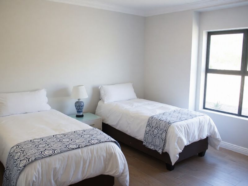 A well-maintained bedroom featuring neutral walls, tiled flooring, and a large window providing natural light.