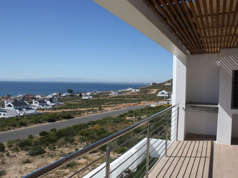Covered balcony featuring a stainless steel balustrade, timber slat ceiling, and built-in braai, offering expansive coastal and neighbourhood views.