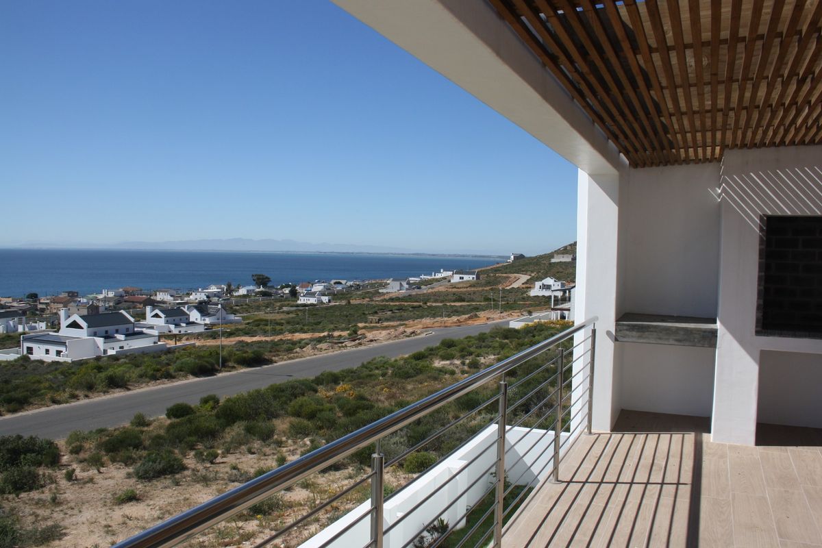 Covered balcony featuring a stainless steel balustrade, timber slat ceiling, and built-in braai, offering expansive coastal and neighbourhood views.