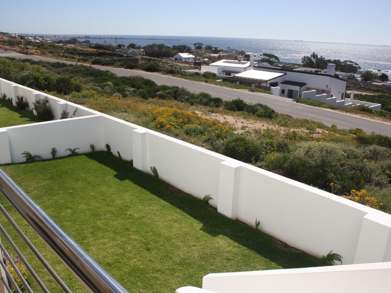 Elevated view overlooking a manicured lawn, boundary wall, and coastal landscape with ocean views.