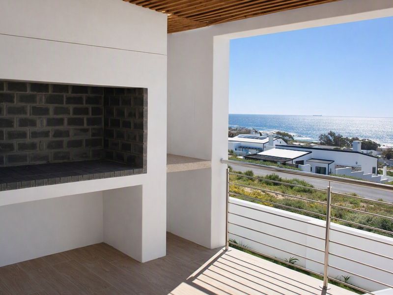 Covered balcony featuring a built-in braai, modern stainless steel balustrade, and expansive ocean views.