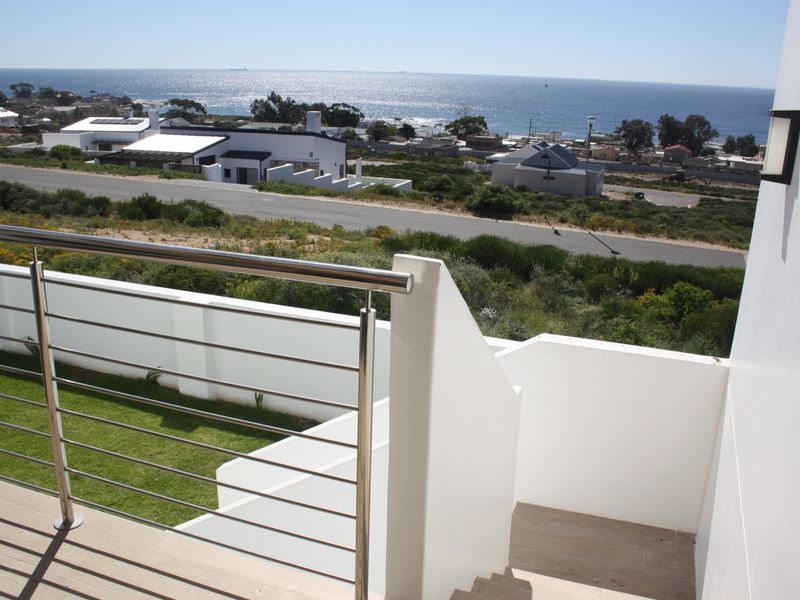 Modern balcony featuring a stainless steel balustrade, tiled flooring, and an elevated view overlooking the coastal landscape and surrounding neighborhood.