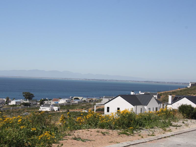 A scenic elevated view overlooking the coastline, ocean, and distant mountain range, showcasing the property's prime location.