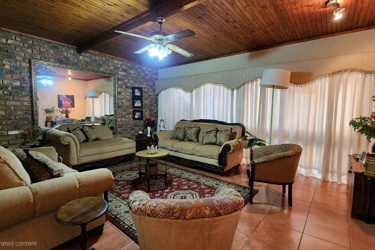 A living room featuring a rustic exposed brick wall, timber-clad ceiling with exposed beams, and tiled flooring.