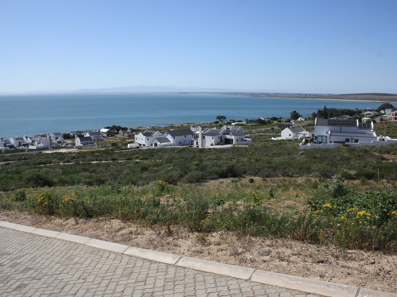Elevated view overlooking the coastal residential area and ocean, showcasing the surrounding landscape and neighborhood setting.