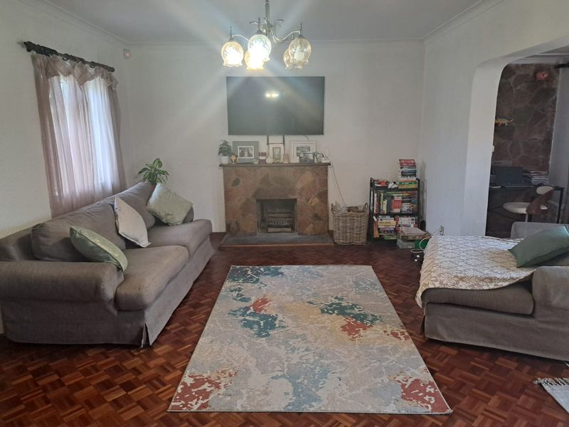 A cozy living room featuring classic parquet flooring, a stone fireplace, and traditional cove cornicing, offering a warm and inviting atmosphere.