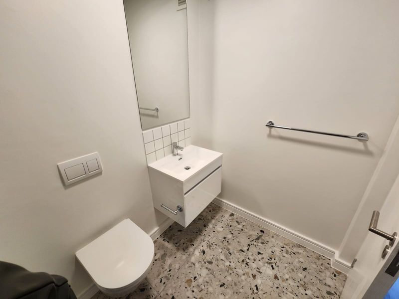 A modern, minimalist bathroom featuring a wall-mounted vanity, basin, wall-hung toilet, and stylish terrazzo floor tiles.