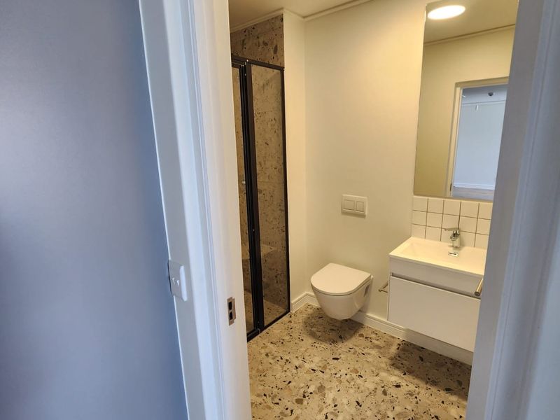 Modern bathroom featuring a wall-hung toilet, vanity with basin, and a walk-in shower with stylish terrazzo-style flooring.