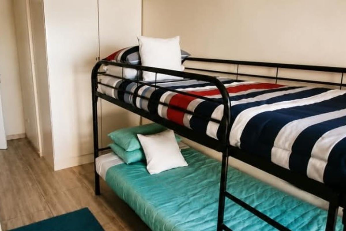 A functional bedroom featuring light-toned laminate flooring and a built-in wardrobe, providing practical storage space.