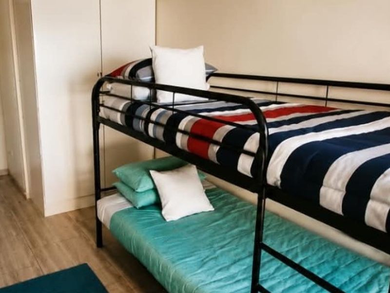 A functional bedroom featuring light-toned laminate flooring and a built-in wardrobe, providing practical storage space.