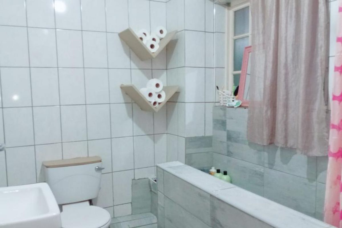 A functional bathroom featuring tiled walls, a built-in bathtub, and a standard toilet. The space requires some maintenance and cosmetic updates.