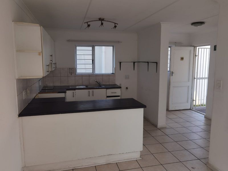 A functional, empty kitchen featuring built-in cabinetry, laminate countertops, and tiled flooring, offering a blank canvas for potential renovation and modernization.