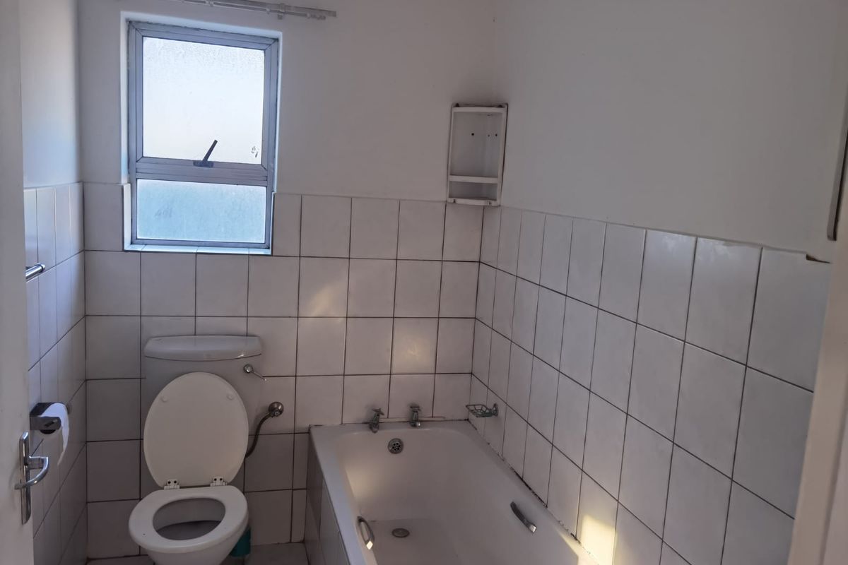 A functional bathroom featuring a standard bathtub, toilet, and tiled wall finishes, offering a blank canvas for potential modernization and renovation.