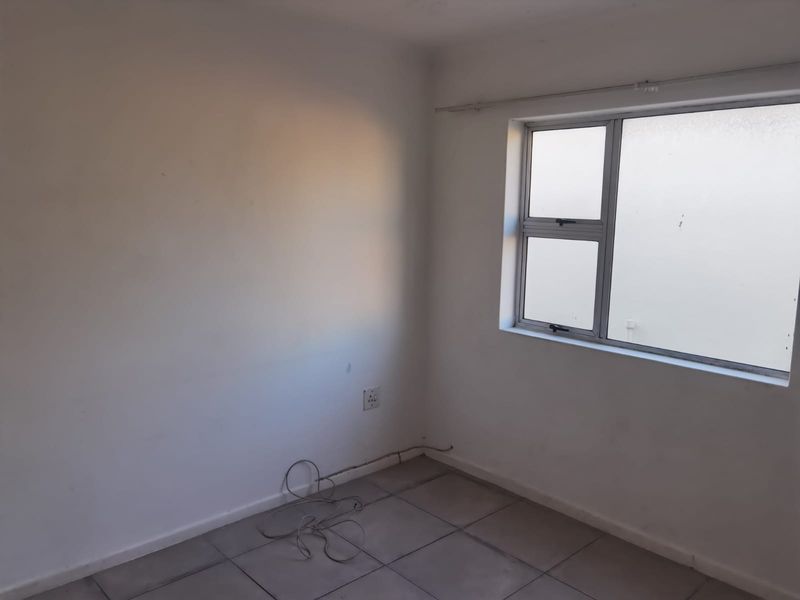 A vacant bedroom featuring neutral tiled flooring and an aluminium-framed window, providing a blank canvas for personalization.