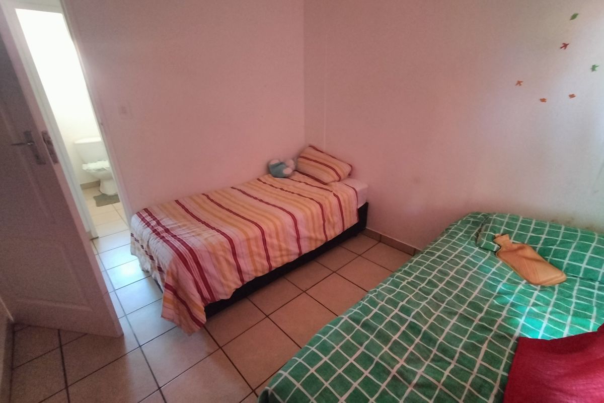 A functional bedroom featuring tiled flooring and direct access to an en-suite bathroom.