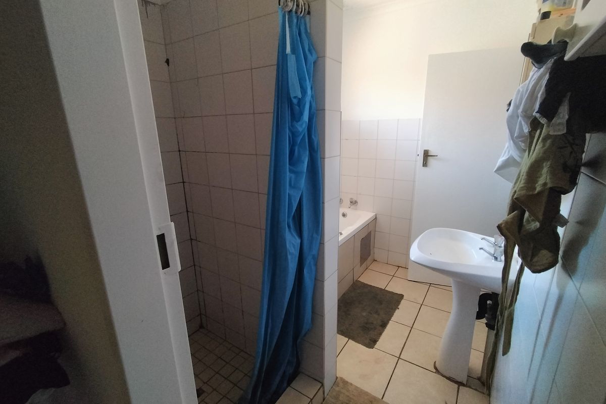 A functional bathroom featuring a pedestal sink, a built-in bathtub, and a separate tiled shower enclosure with dated finishes.