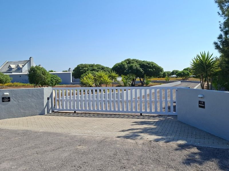 A secure entrance to the small holding featuring an automated sliding gate, paved driveway, and well-maintained boundary walls.