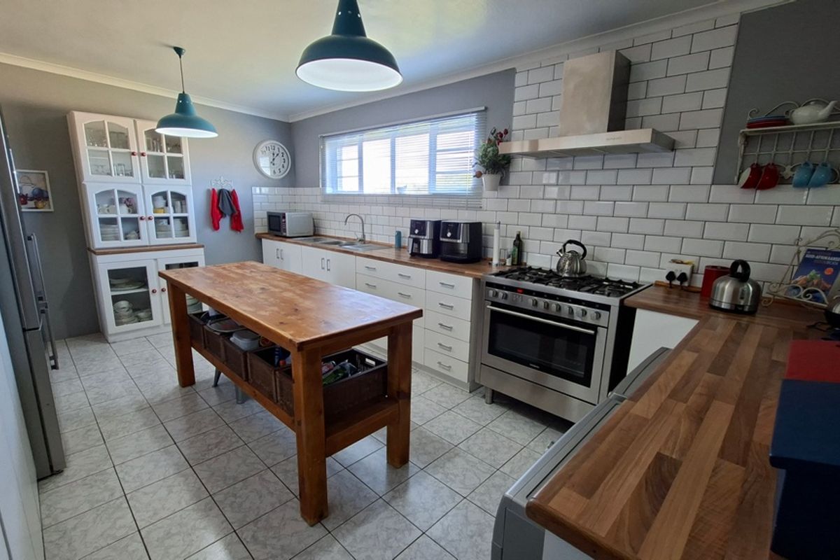A well-maintained kitchen featuring subway tile backsplash, stainless steel gas stove, extractor fan, wooden countertops, and ample built-in cabinetry with a central island.
