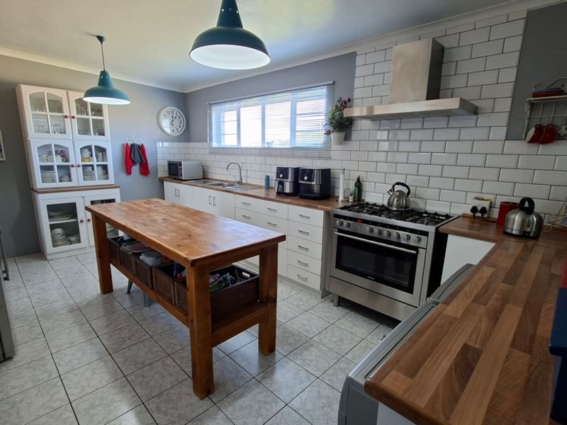 A well-maintained kitchen featuring subway tile backsplash, stainless steel gas stove, extractor fan, wooden countertops, and ample built-in cabinetry with a central island.