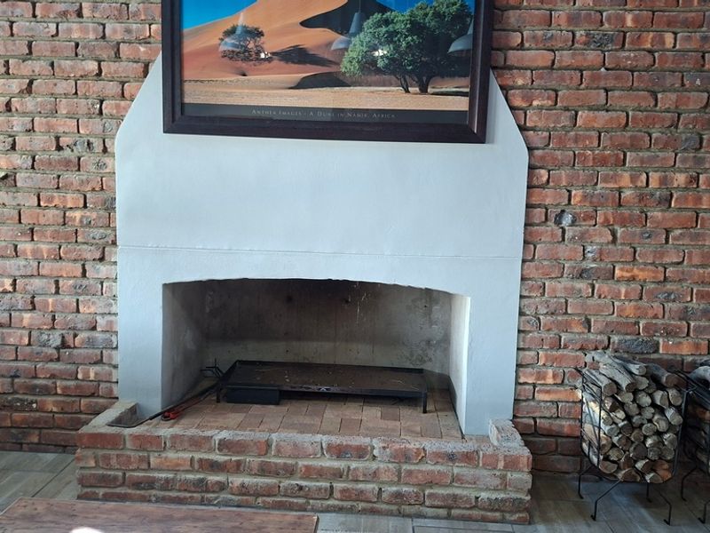 A cozy living area featuring a prominent exposed brick wall and a traditional built-in brick fireplace with a hearth.