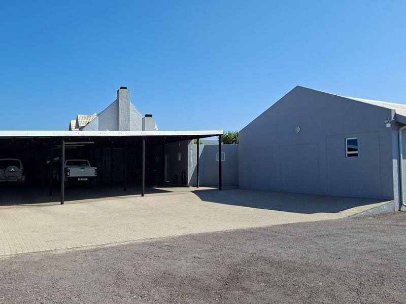 Spacious paved driveway area featuring a large covered carport and well-maintained exterior building facades.