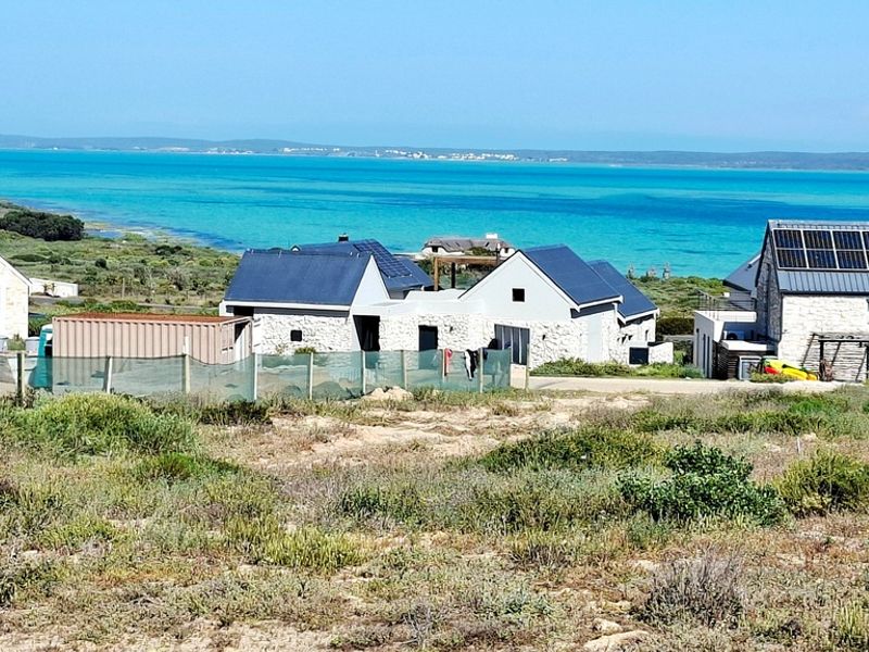 A scenic view overlooking the coastal landscape and turquoise ocean waters, showcasing the surrounding residential properties and natural environment.