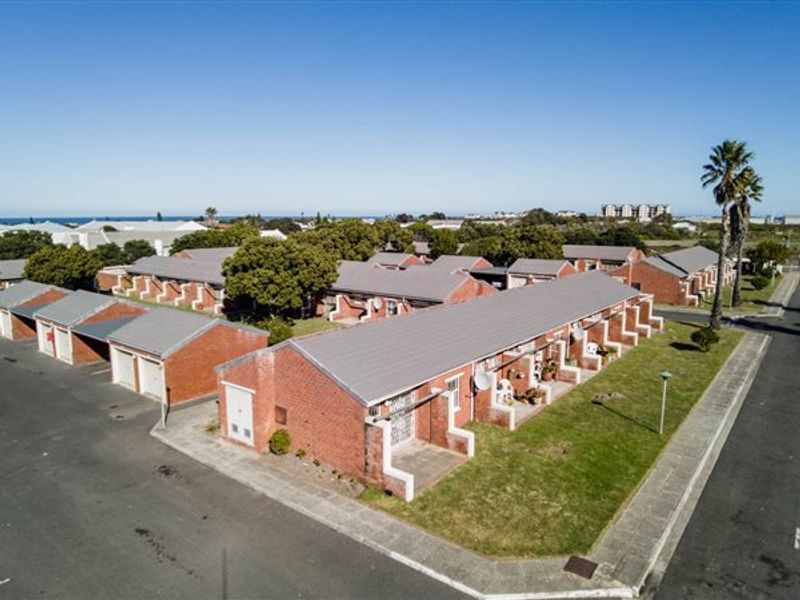 Aerial view of a townhouse complex featuring brick construction, tiled roofs, paved driveways, and communal garden areas in a residential setting.