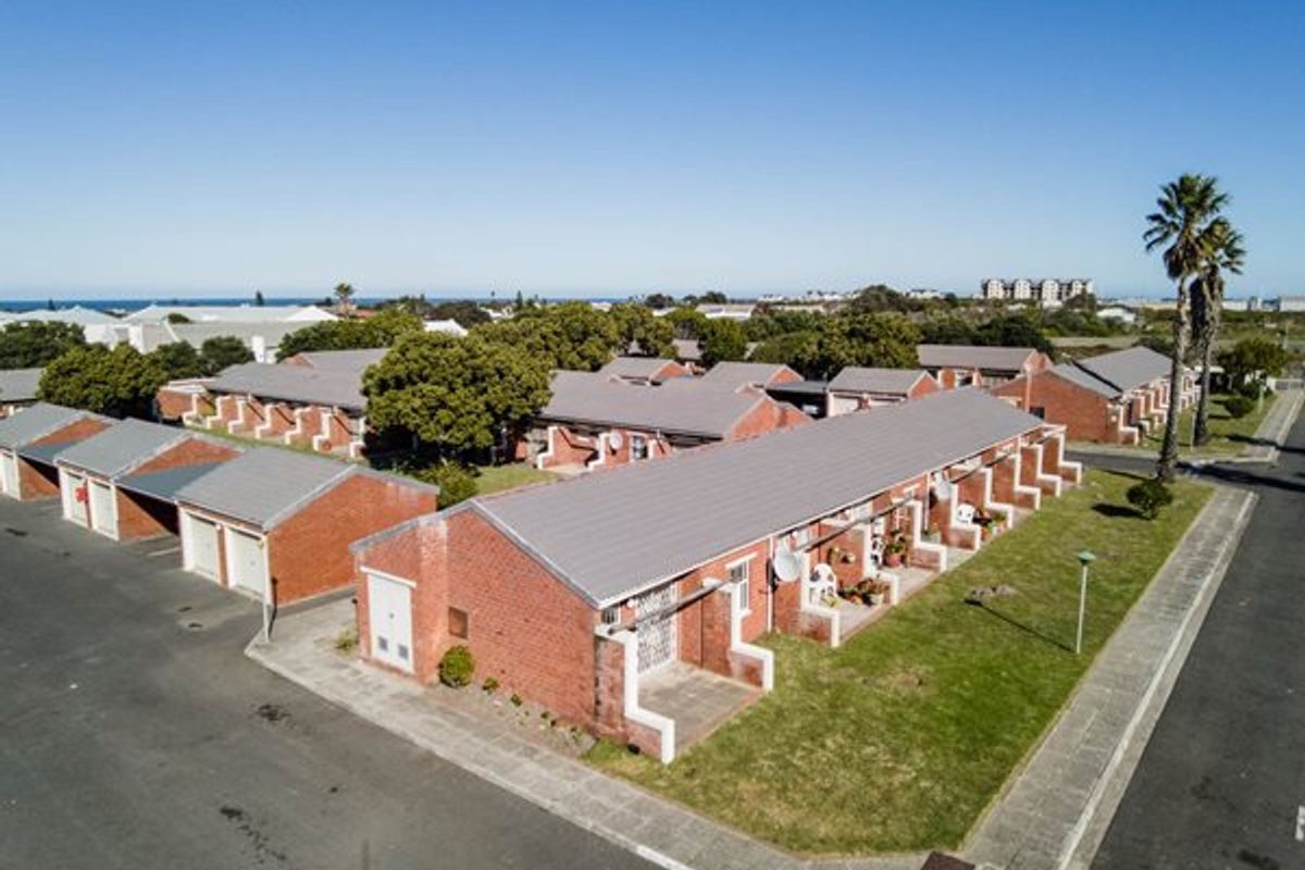 Aerial view of a townhouse complex featuring brick construction, tiled roofs, paved driveways, and communal garden areas in a residential setting.