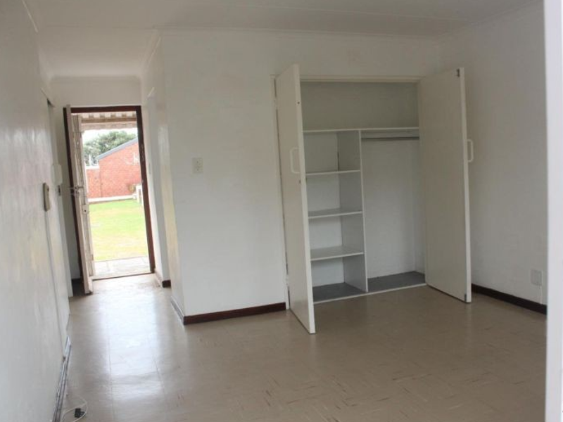 An empty bedroom featuring a built-in wardrobe, vinyl flooring, and direct access to an outdoor area.