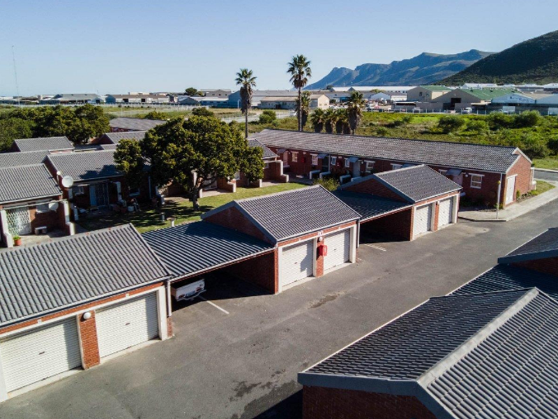 Aerial view of a townhouse complex featuring brick construction, tiled roofs, and integrated garage and carport parking facilities.