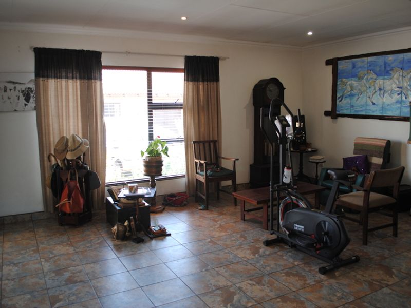 A spacious living area featuring durable tiled flooring, recessed downlighting, and a large window providing natural light.