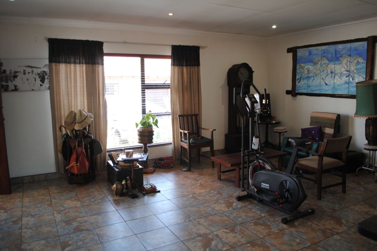 A spacious living area featuring durable tiled flooring, recessed downlighting, and a large window providing natural light.
