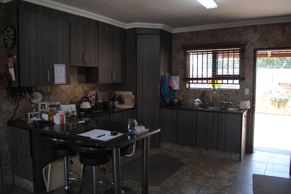 A functional kitchen featuring dark wood cabinetry, granite countertops, a double bowl sink, and tiled finishes with direct access to the exterior.