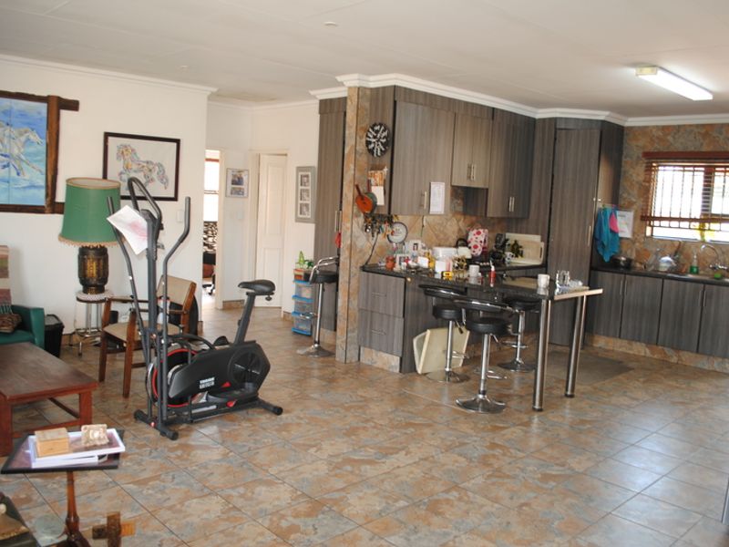 Open-plan living and kitchen area featuring tiled flooring, modern cabinetry, granite countertops, and a breakfast bar, providing a functional and connected living space.
