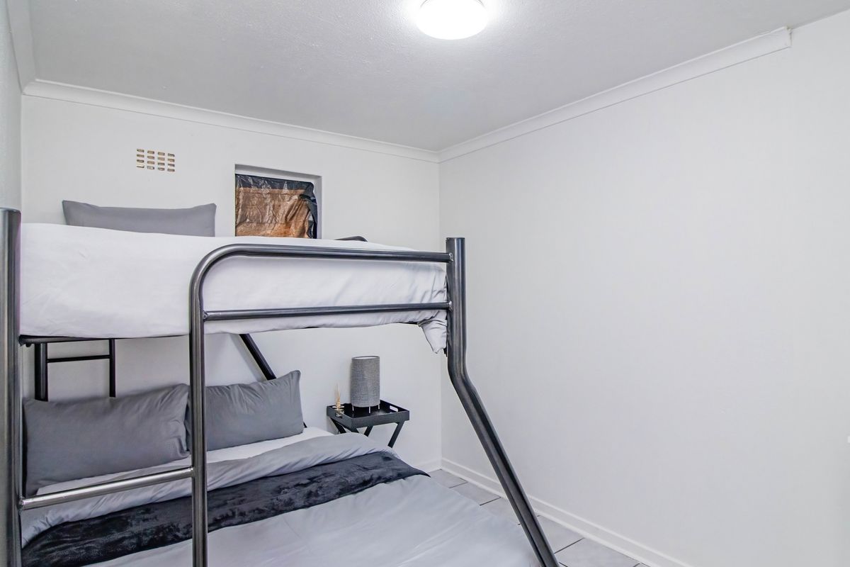 A compact bedroom featuring tiled flooring, coving, and a ceiling light fixture, providing a functional space for sleeping.