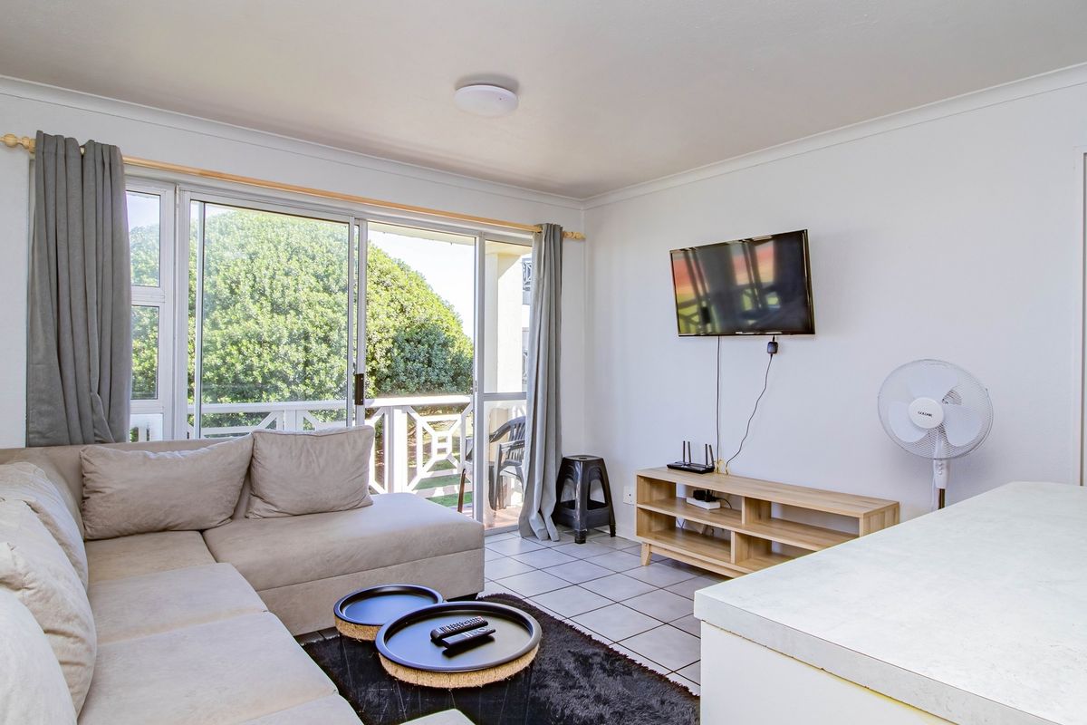 A bright living room featuring tiled flooring and large sliding glass doors that provide access to an outdoor balcony area.