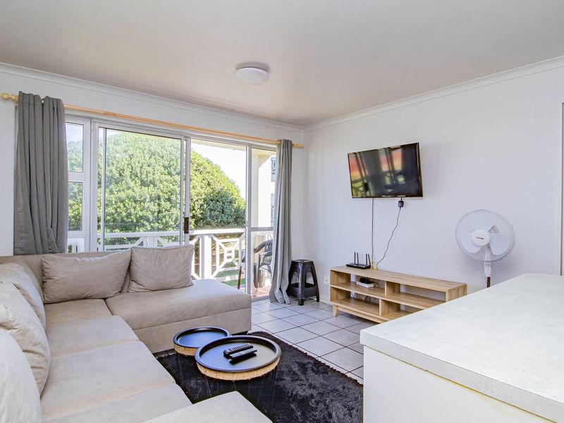 A bright living room featuring tiled flooring and large sliding glass doors that provide access to an outdoor balcony area.